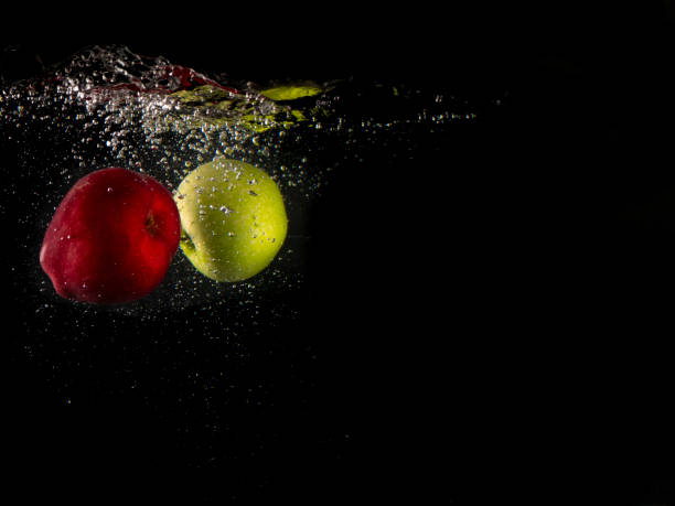 istock green and red apple falling into splashing water on black background and copy space 1131754349