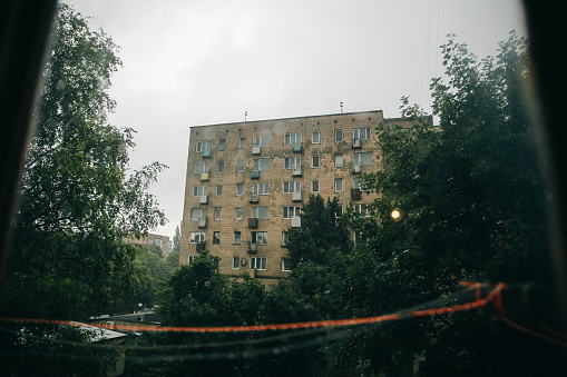 Old post soviet house in the dark city. USSR architecture in the rain. Depressing poor regions.