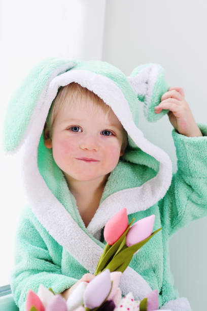 cute baby boy in a rabbit costume with a bouquet of flowers on Mother's Day. cute baby boy in a rabbit costume with a bouquet of flowers on Mother's Day. Easter Bunny, March 8, Spring holding child flower april stock pictures, royalty-free photos & images