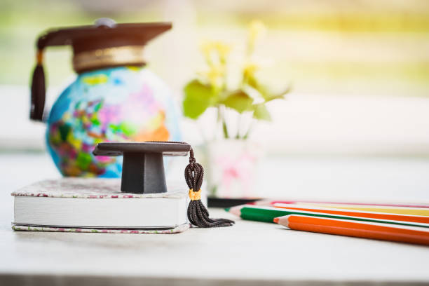 istock Graduate or Education knowledge learning study abroad concept : Graduation cap on book with blur of Europe earth world globe, with color pencils on wood floor. Work and travel. Back to School 1131757139