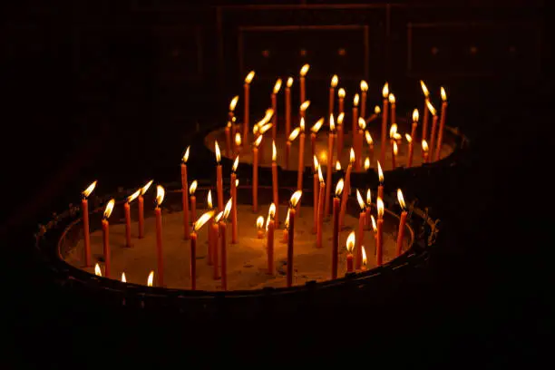 Photo of Candles lit in a stand with sand in a church in Prague