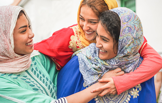 Jóvenes amigos islámicos divirtiéndose al aire libre-felices amigos árabes riendo y sonriendo juntos-amistad, religión, cultura étnica y concepto de la juventud-enfoque en la cara superior de la muchacha photo