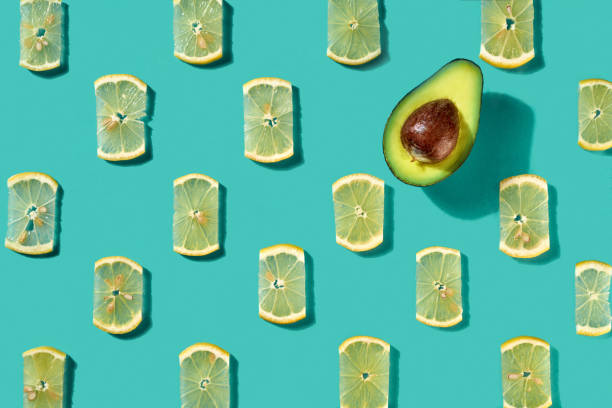 istock Pattern made of lemon slices and half avocado on a blue background. Food background. Flat lay 1131768936