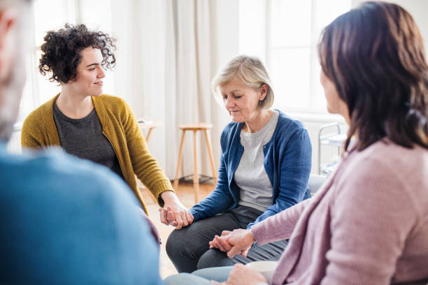 Men and women sitting in a circle during group therapy, supporting each other. Serious men and women sitting in a circle during group therapy, supporting each other. group of ladies talking stock pictures, royalty-free photos & images