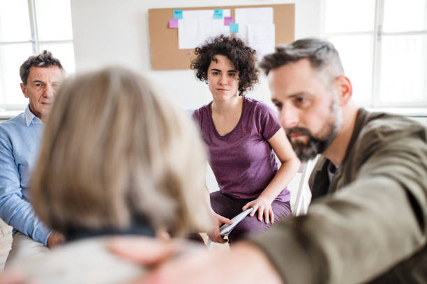 istock Men and women sitting in a circle during group therapy, supporting each other. 1131769057