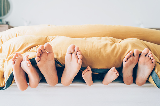 Family feet from under blanket