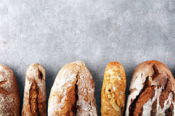 istock Assortment of baked bread and bread rolls on stone table background 1131771416