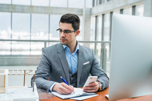 istock Young businessman or architect with computer and smartphone in office, working. 1131771639