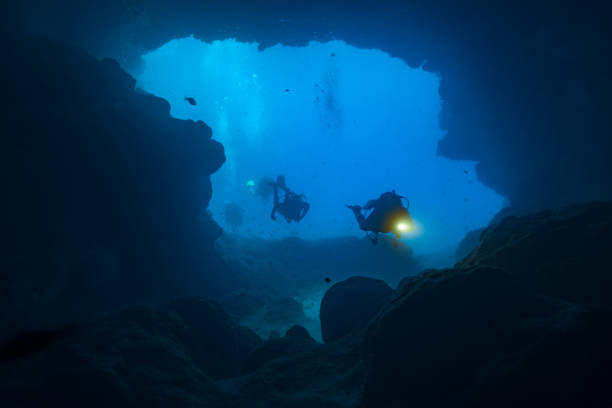 höhlentaucher, die die höhlen von santa maria, comino, malta erkunden - spelunking stock-fotos und bilder