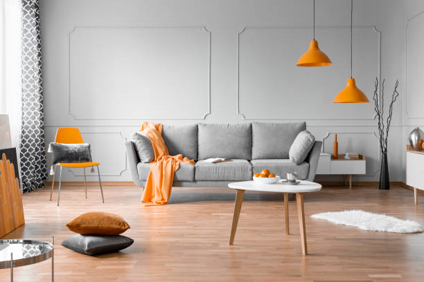 design d'intérieur de salon à la mode avec canapé gris, table basse en bois et accents oranges - gray hair photos photos et images de collection