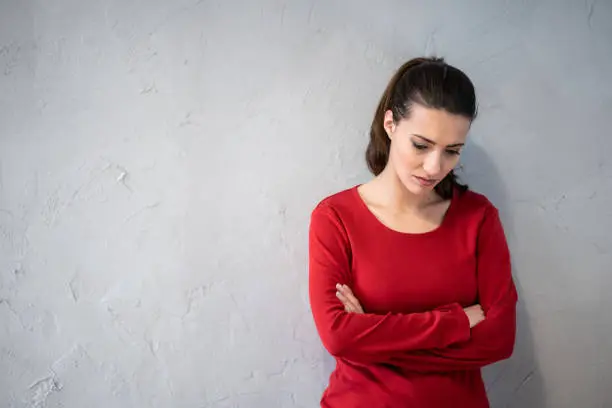 Photo of Unhappy woman woman standing with arms crossed on gray background