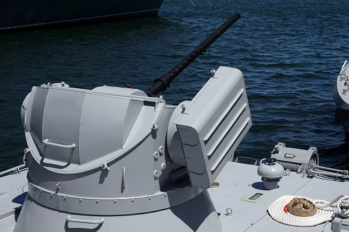 Naval ship artillery gun barrel on a blue sea background. copy space, selective focus, narrow depth of field