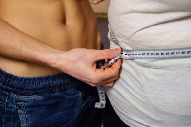 weight loss, personal trainer, motivation, fitness weight loss, personal trainer, dietician, fitness, motivation, healthy lifestyle. cropped portrait of sporty fit muscle man with perfect body measuring waist of overweight fat woman with tape measure waist trainer for men stock pictures, royalty-free photos & images