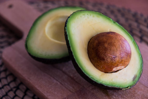 istock Avocado fruit cut in half on wooden cutting board 1131779677