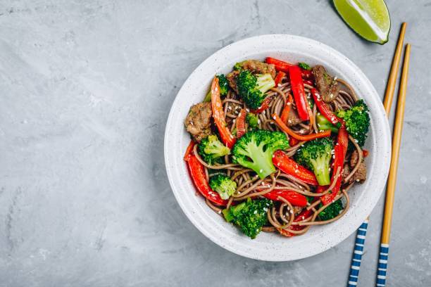 fritada do stir do macarronete da carne com brócolis, cenouras e pimentas de sino vermelhas - green bell pepper - fotografias e filmes do acervo