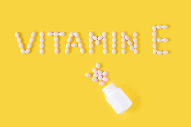 istock Vitamin E pills dropped from bottle on yellow background. Flat lay, top view, free copy space. 1131784892
