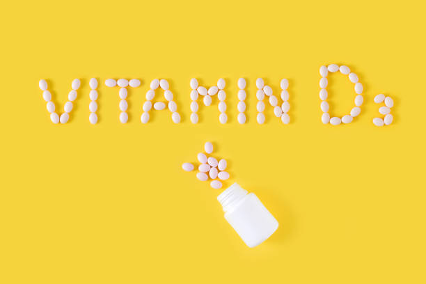 istock Vitamin D3 pills dropped from bottle on yellow background. Flat lay, top view, free copy space. 1131784894