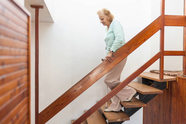 Elderly woman at home using a cane to get down the stairs Elderly woman at home using a walking cane to get down the stairs railing photos stock pictures, royalty-free photos & images