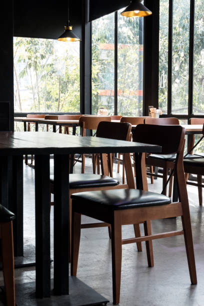 istock Table and chair set in modern cafe minimalistic interior design with big window and hanging ceiling lamps 1131790414