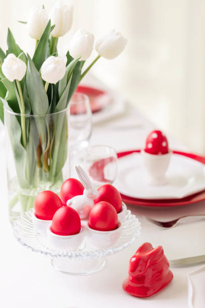 istock Happy easter. Decor and table setting of the Easter table is a vase with white tulips and dishes of red and white color. Easter colored eggs with white polka dots. 1131791484