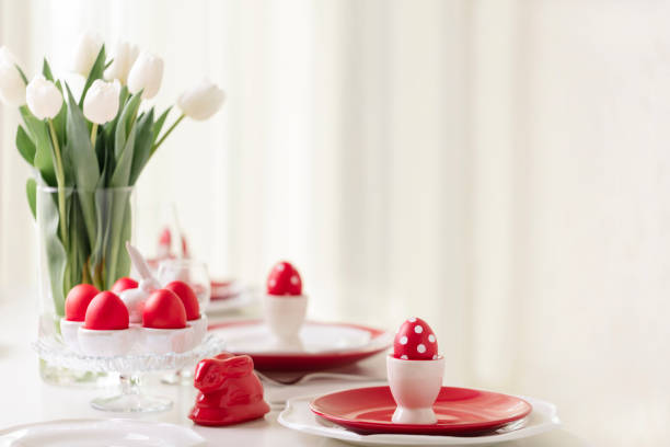 istock Happy easter. Decor and table setting of the Easter table is a vase with white tulips and dishes of red and white color. Easter colored eggs with white polka dots. 1131791489