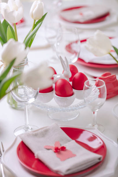 istock Happy easter. Decor and table setting of the Easter table is a vase with white tulips and dishes of red and white color. Easter colored eggs with white polka dots. 1131791492
