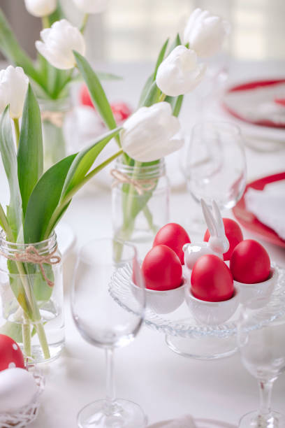 istock Happy easter. Decor and table setting of the Easter table is a vase with white tulips and dishes of red and white color. Easter colored eggs with white polka dots. 1131791498