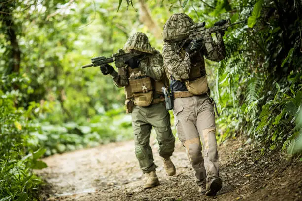 Military/airsoft soldiers in the jungle wearing tactical gear and with rifles