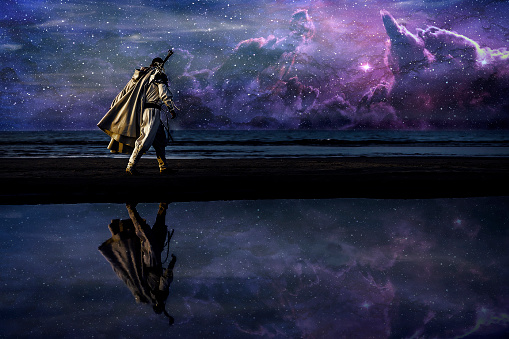 Silhouette of assassin in white costume walking by the night at the sea with sword. Beautiful and colorful galaxy on the sky on background.