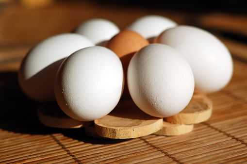 Eggs in a circle: 6 white, one brown in the middle.