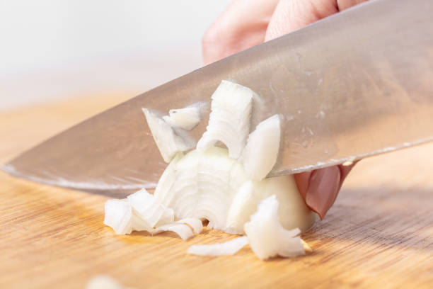 istock cook cuts onion on a wooden board 1131797113