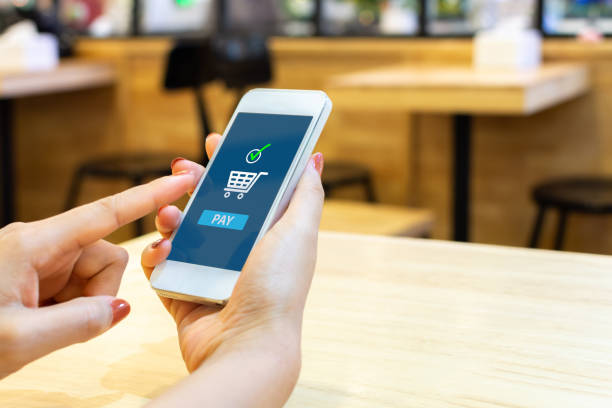 istock Concept online payment mobile technology. Hand of female using smartphone touching pay button mobile banking application in restaurant 1131809387