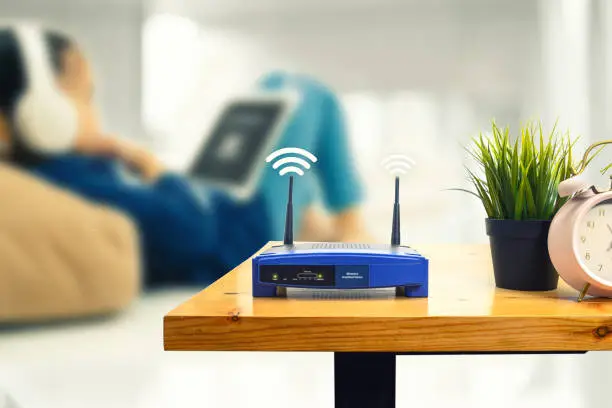 Photo of closeup of a wireless router and a man using smartphone on living room at home ofiice