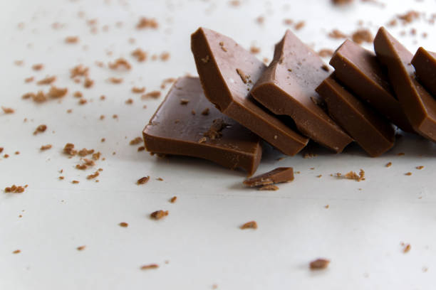 istock Broken chocolate pieces on white background, delicious sweet snack background 1131811040