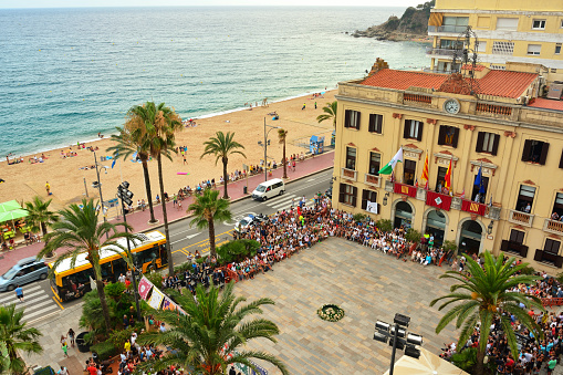Lloret de Mar, Spain. July 24.2015:  The central square of the city on the coast. In the central square of the city everything is ready for the holiday. A lot of people are sitting in the stands and waiting for the start. The orchestra is ready. The building is decorated with coats of arms and flags.