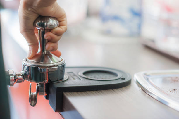 istock Barista holding tamper of pressing ground coffee making 1131821693