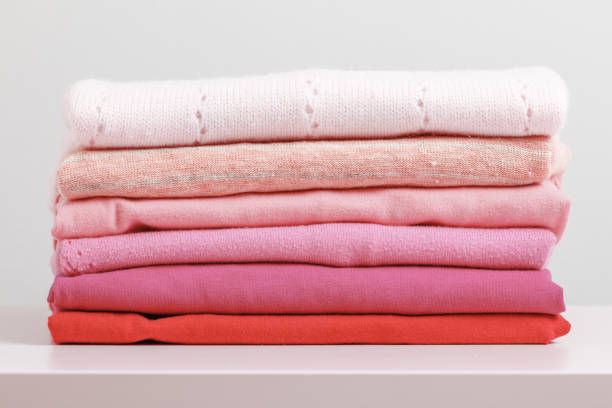 istock On a pink dresser is a stack of folded clothes. Gray background. Close-up 1131824529