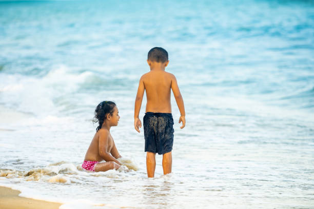 istock Two Kids Playing Sand and Water Wave on the Beach. 1131828447
