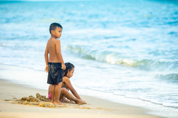 istock Two Kids Playing Sand and Water Wave on the Beach. 1131828485