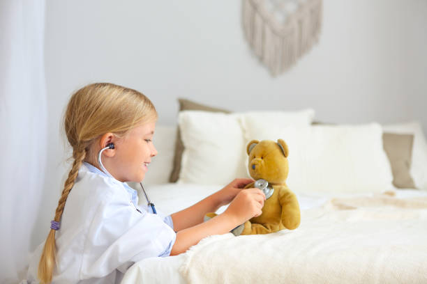 istock Little blond girl with stethoscope playing with teddy bear 1131829950