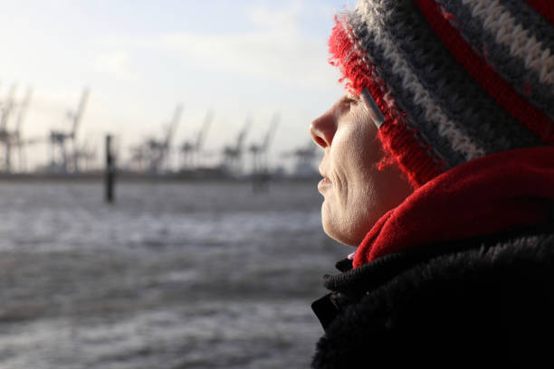 woman enjoying the sun on a winter day at the river elbe in hamburg, germany - winter women zen like photography imagens e fotografias de stock