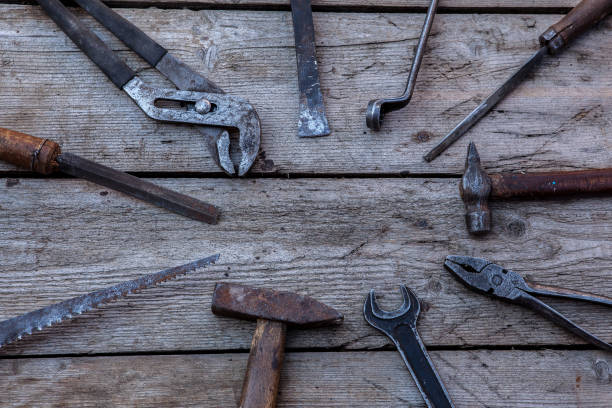 istock Old, rusty tools lying on a black wooden table. Hammer, chisel, hacksaw, metal wrench.Copy space 1131832910