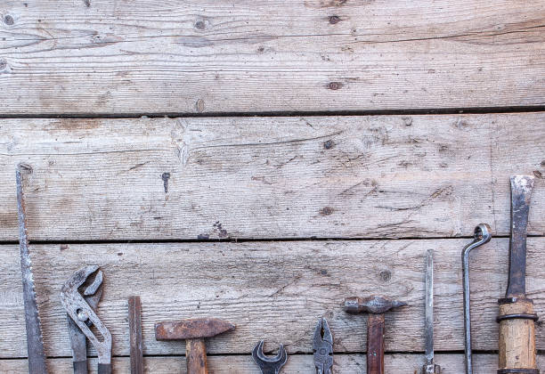 istock Old, rusty tools lying on a black wooden table. Hammer, chisel, hacksaw, metal wrench.Copy space 1131832925