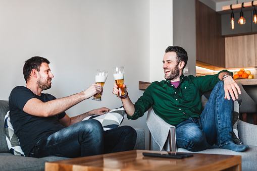 Two guys drinking beer and having fun in the living room