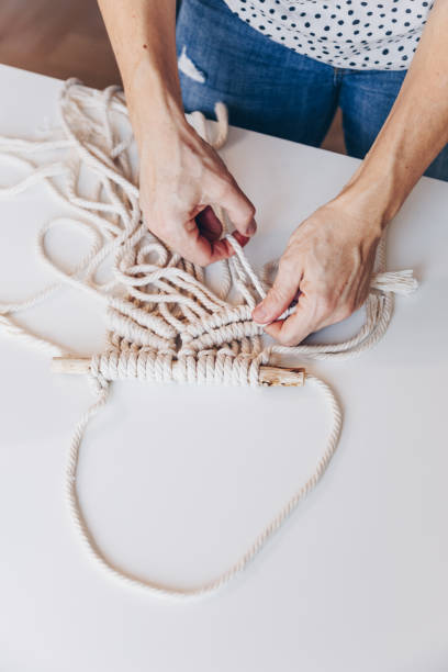 istock Close up of female hands weaving macrame in a home workshop. 1131833593