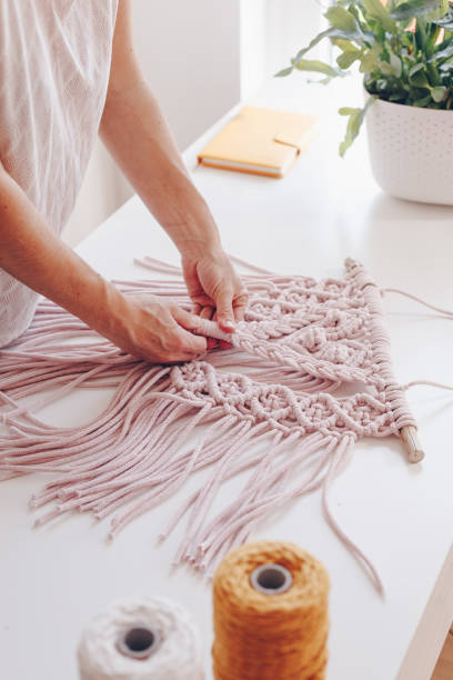 Close up of female hands weaving macrame in a home workshop.