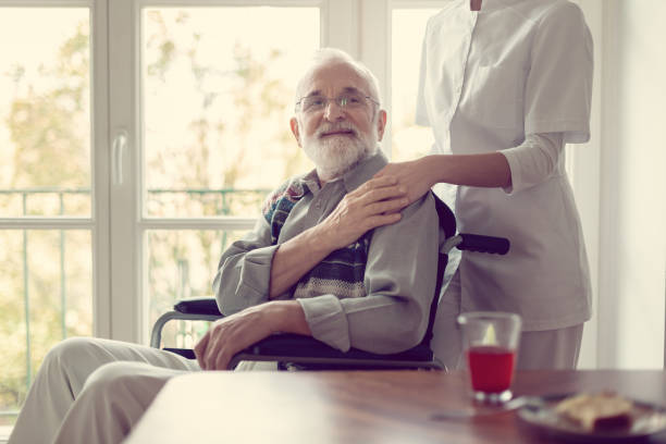 白い制服の役に立つ看護婦を持つ老人ホームの上級患者 - doctor male men white ストックフォトと画像