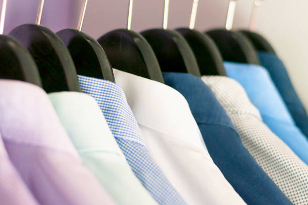 Several men's shirts of different colors on the hangers. Selective focus.