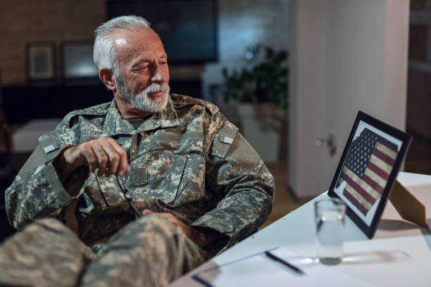 Feeling proud because he served to US forces! Smiling mature army soldier feeling proud and admiring the American flag in picture frame while relaxing in the office. patriotic man stock pictures, royalty-free photos & images