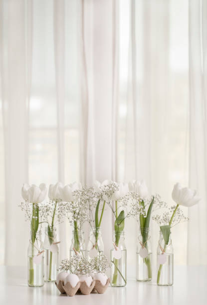 istock White tulips in bottles with Easter decoration in the form of eggs on a white table. 1131844895